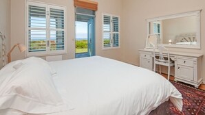 A bedroom with a bed, a dresser, a mirror, and a window with shutters.