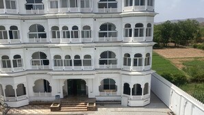 Un edificio de varios pisos con zona de piscina, con balcones y ventanas arqueadas.