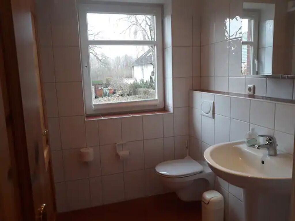 A small bathroom with a toilet, sink, and window.