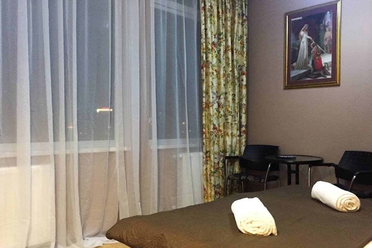 Habitación de hotel con cama, dos sillas, una mesa y un cuadro en la pared.