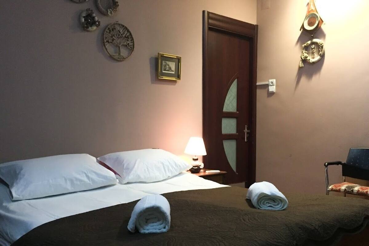 Una habitación de hotel con una cama, una mesita de noche con lámpara, una puerta y adornos en la pared.