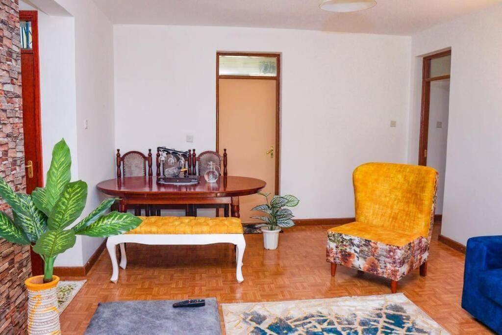 A living room with a wooden dining table, a yellow armchair, a bench, and a potted plant.