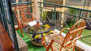 Ein Balkon mit Korbstühlen, einem Glastisch und einem Blumentopf.