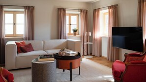 Una sala de estar moderna con un sofá, una mesa de centro, un sillón rojo, un televisor de pantalla plana y una lámpara de pie.