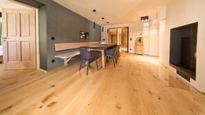 A modern kitchen with wooden flooring, a dining area with a long table and chairs, and a fireplace.