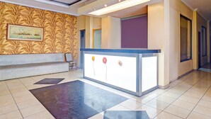 A reception area with a reception desk, a bench, and a patterned wall. - Collection O Tanah Abang Near Stasiun Tanah Abang  Formerly Hotel Bimo Slipi (Jakarta)