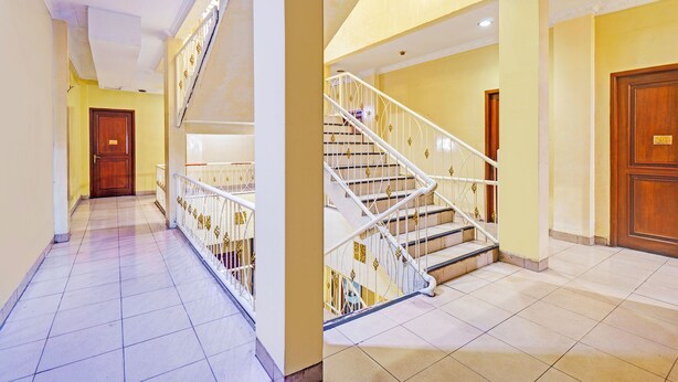 A hotel corridor with a staircase, a wooden door, and a tiled floor. - Collection O Tanah Abang Near Stasiun Tanah Abang  Formerly Hotel Bimo Slipi (Jakarta)