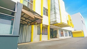 A modern building with yellow and white exterior walls, large windows, and a covered entrance area. - Collection O Tanah Abang Near Stasiun Tanah Abang  Formerly Hotel Bimo Slipi (Jakarta)