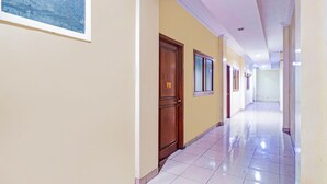 A long, narrow hallway with cream walls and a tiled floor. - Collection O Tanah Abang Near Stasiun Tanah Abang  Formerly Hotel Bimo Slipi (Jakarta)