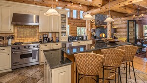 A spacious kitchen with a large island, stainless steel appliances, and a stone fireplace.