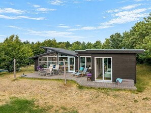 A modern house with a deck, outdoor seating, and a large sliding glass door.