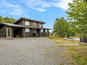 A two-story house with a gravel driveway and a fenced yard.
