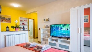A hotel room with a bed, a TV, a wardrobe, and a bathroom visible through an open door. - Apartments Milok (Piran)