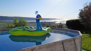 An inflatable duck in a swimming pool with a scenic view of hills and a body of water in the background. - Apartments Milok (Piran)