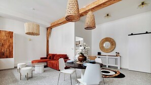 Un espace repas moderne avec une table ronde, des chaises blanches et un canapé rouge.