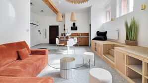 A modern living room with a red sofa, a round coffee table, and a kitchen area with a dining table and chairs.
