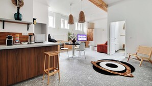 A modern kitchen with a wooden island, bar stools, and a dining area with a TV.