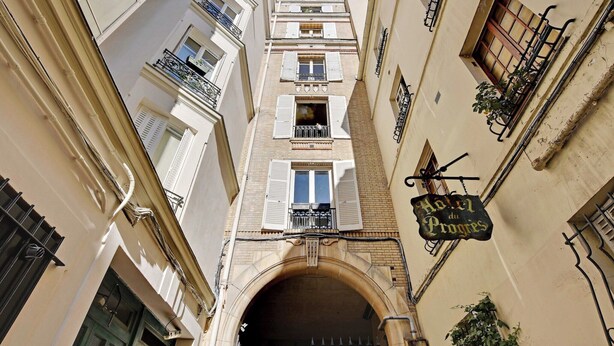 A narrow alleyway with a building featuring a sign for 'Hotel du Progres'.