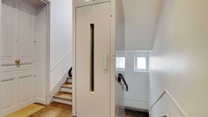 A staircase with a white door at the top, a handrail, and a wooden floor.
