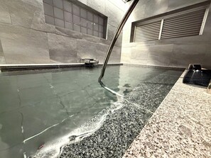 A spa pool with a water jet feature, a bench, and a ventilation system on the wall. - BAKERY HOTEL SHIRAHAMA (Shirahama)