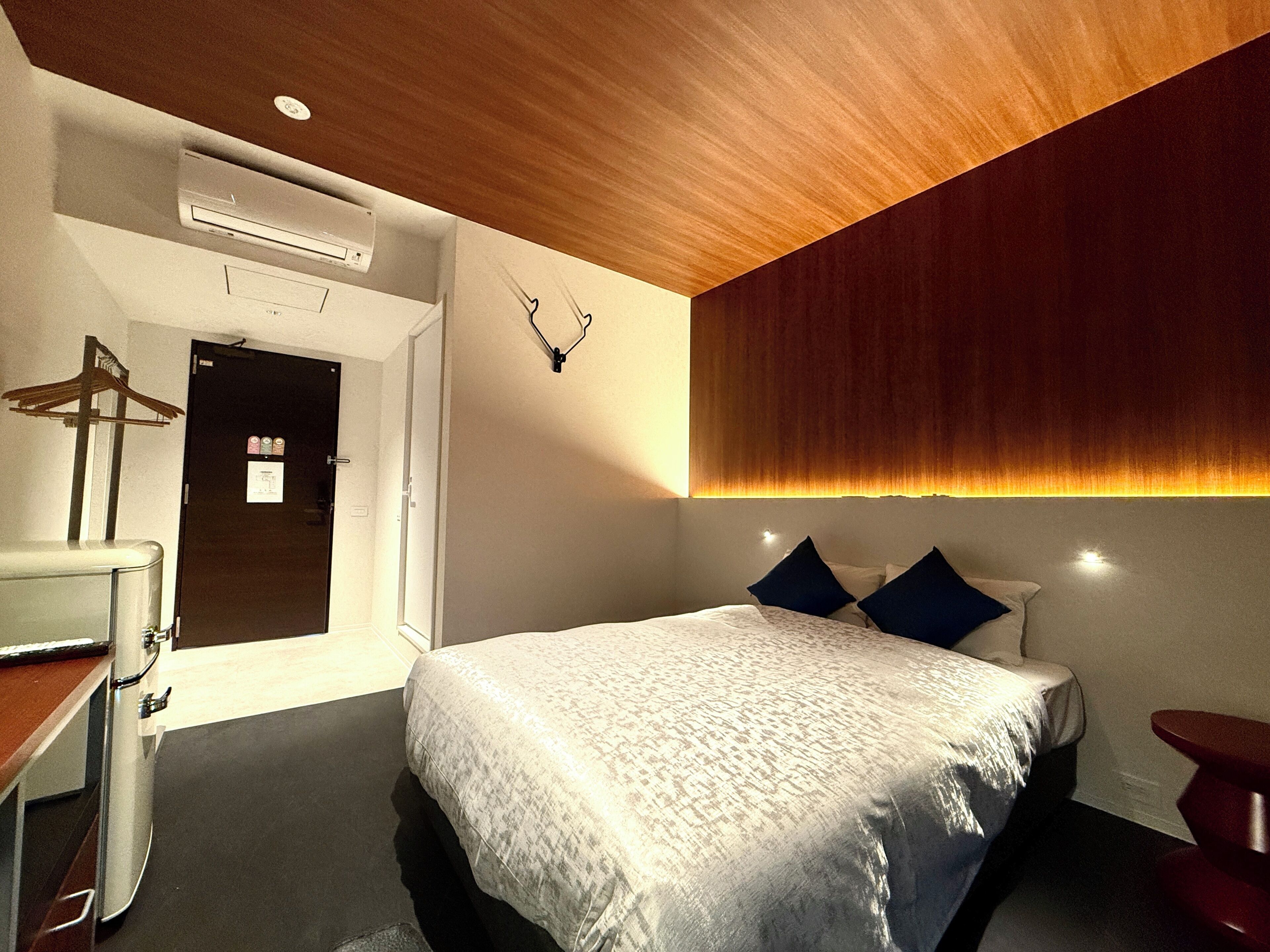 Una habitación de hotel moderna con una cama, una mesita de noche y un escritorio con una silla.