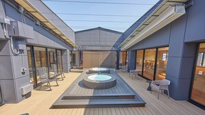 Une terrasse extérieure moderne dotée de deux bains à remous, de coins salon et d’une terrasse en bois.
