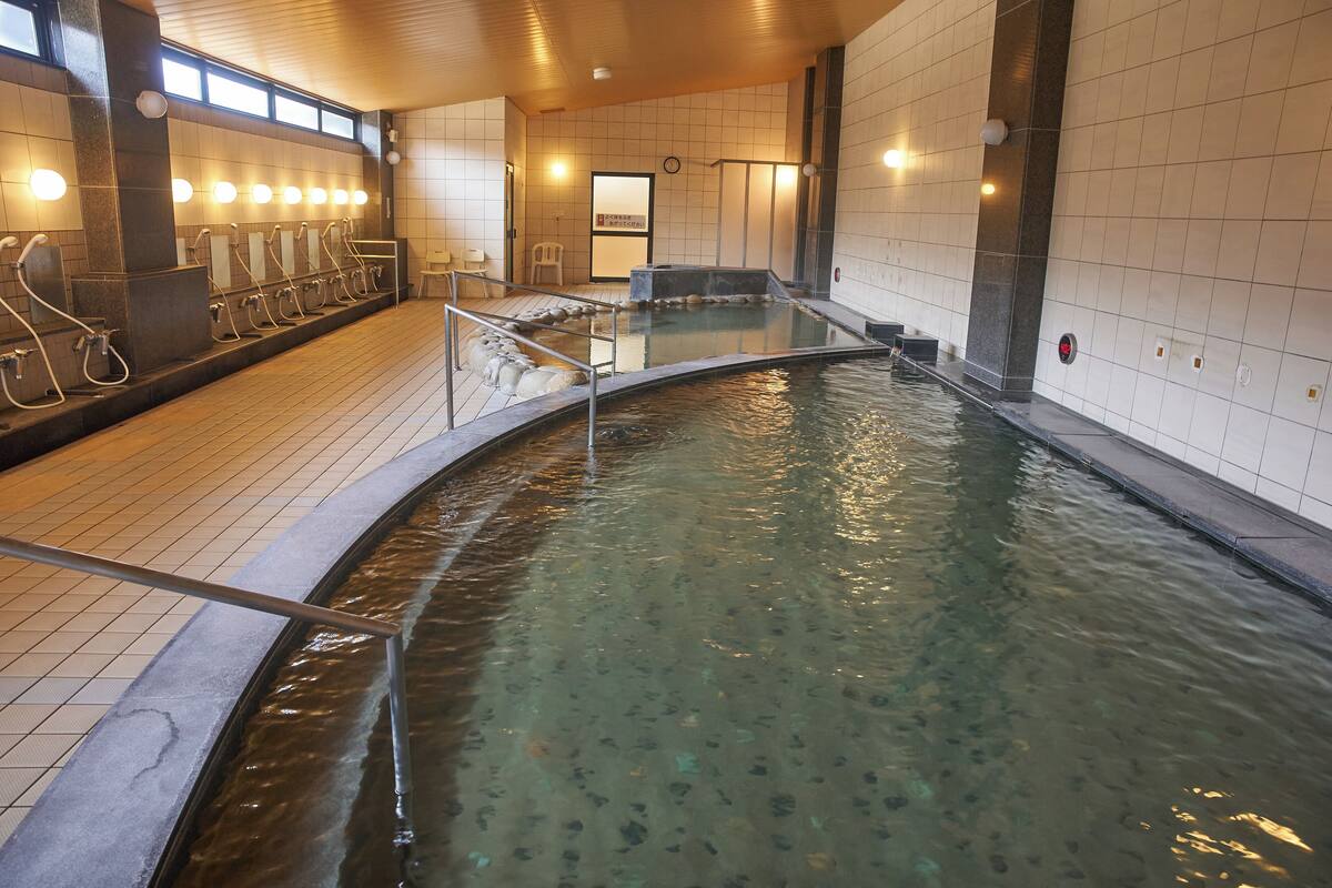 A public bath area with multiple changing rooms, a central pool, and a seating area.