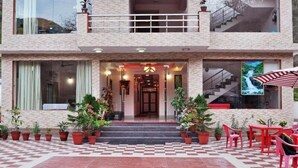 A hotel entrance with a checkered floor, potted plants, and outdoor seating. - Sapphero Chanakya Resort  (Narendranagar)
