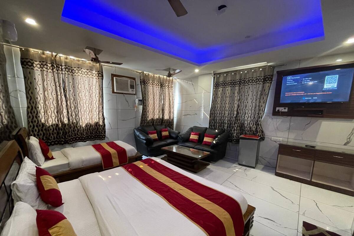 Et moderne hotelværelse med to senge, en sofa, et fjernsyn og et skrivebord.