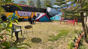 An outdoor area with a mural, a tent, and a red bench. - Sapphero Chanakya Resort  (Narendranagar)