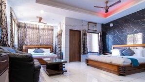 A modern living room with a sofa, two beds, a coffee table, and a ceiling fan. - Sapphero Chanakya Resort  (Narendranagar)