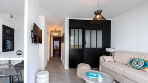 Een moderne woonkamer met een bank, salontafel en een eethoek, inclusief een televisie en magnetron.
