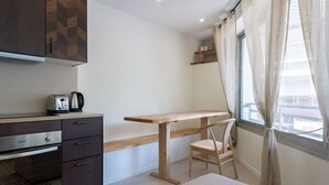 A compact kitchen with a toaster, a coffee maker, and a wooden table.