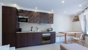 A modern kitchen with dark wood cabinets, a built-in oven, and a wooden dining table with a chair.