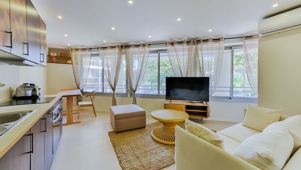 A modern living room with a sofa, a TV, and a dining area with a table and chairs.