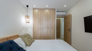 A bedroom with a bed, a hanging light fixture, a wardrobe, and a door.
