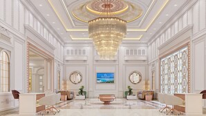 A luxurious lobby with a grand chandelier, elegant furniture, and a large painting on the wall. - OZEN MANSION KOLKATA (Barasat)