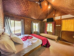 Une pièce comprenant un lit, un banc, un ventilateur de plafond et des fenêtres avec des rideaux.