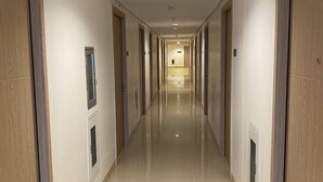 A long, narrow hallway with doors on both sides, leading to a central area with a light fixture on the ceiling.