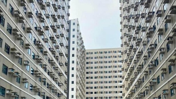 A swimming pool flanked by high-rise residential buildings with balconies.