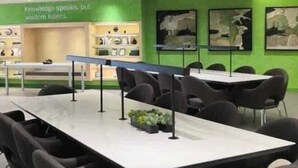 A conference room with a long table and chairs, green walls, and artwork.