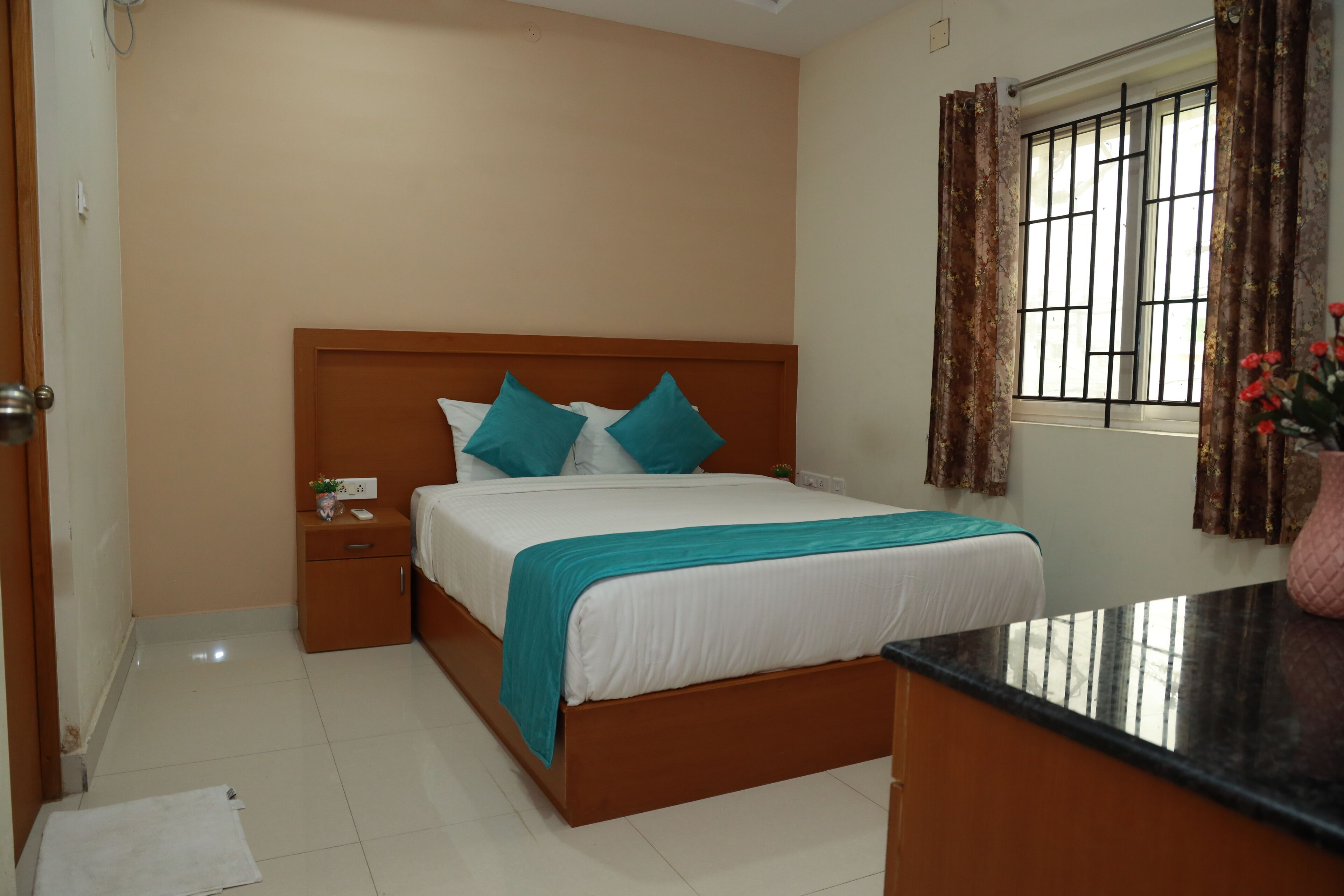 A neatly arranged bedroom with a bed, bedside table, and a window with curtains.