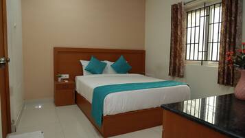 A neatly arranged bedroom with a bed, bedside table, and a window with curtains.