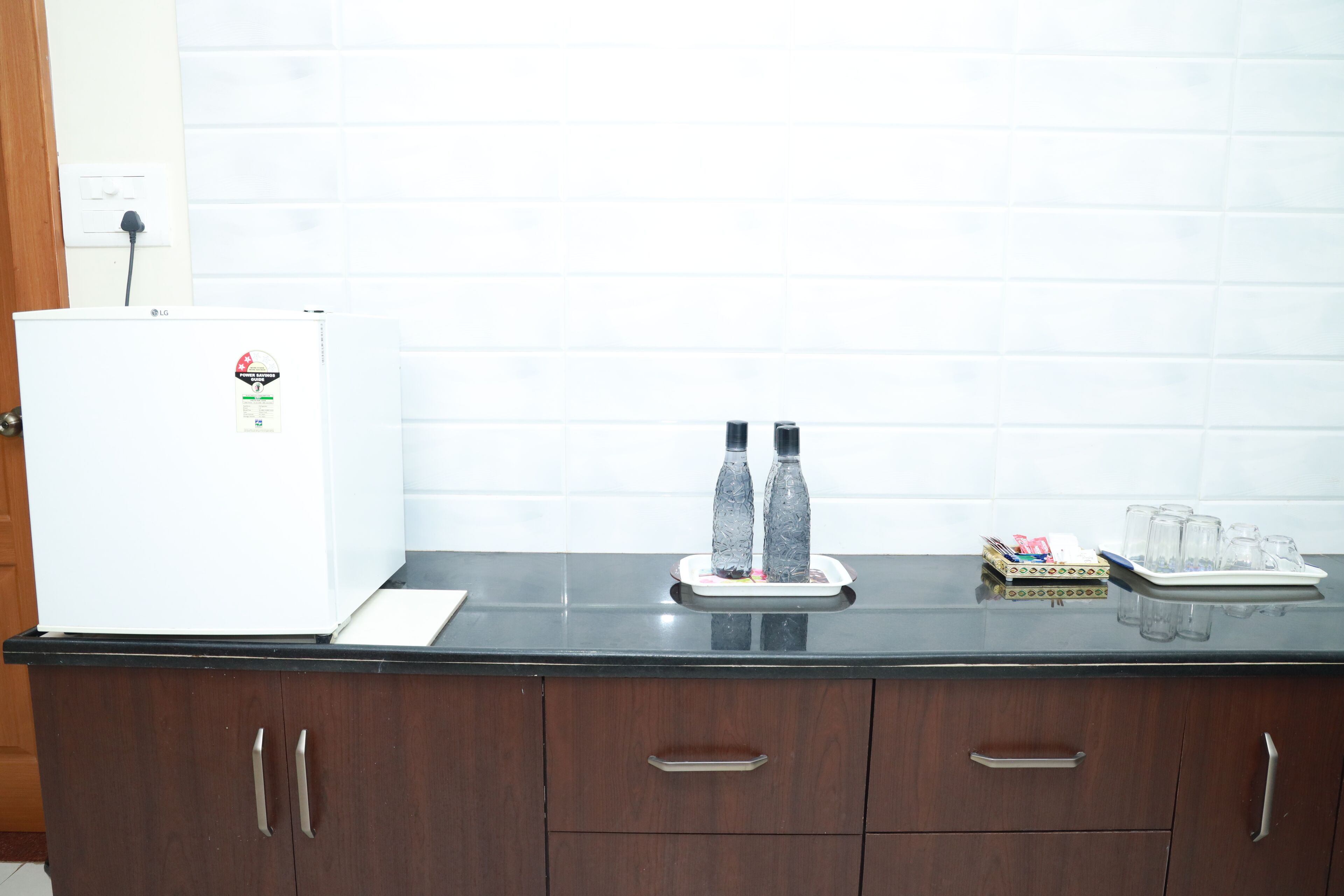 A kitchen with a white refrigerator, dark wooden cabinets, and a black countertop.