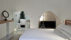 A bedroom with a wooden bed, a bedside table, a mirror, and an arched doorway leading to a bathroom. - Unique Trullo enchantment among olive trees (Noci)