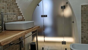 A modern bathroom with a large arched doorway, a sink with a wooden countertop, and a bathtub. - Unique Trullo enchantment among olive trees (Noci)