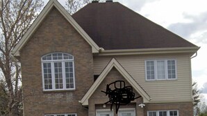 A two-story house with a symmetrical facade, a central entrance with a door and steps, and a mailbox.