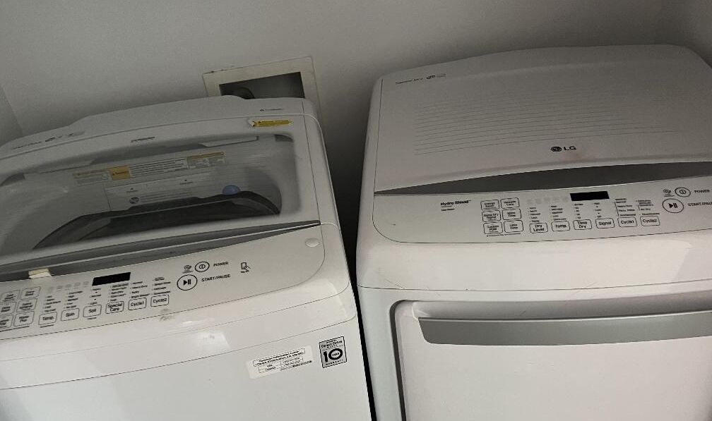 Two white laundry machines with control panels, one with a digital display and the other with buttons.