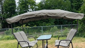 A covered patio area with two chairs and a table.
