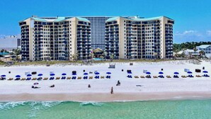 A beachfront hotel with multiple floors, a pool, and a beach with sun loungers.